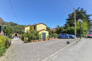 A yellow building with a red roof, a paved driveway, and a parked blue car.