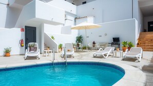 A pool area with lounge chairs, a table, and a grill. - Apartment 'White Suites' with Shared Pool, Wi-Fi and Air Conditioning (Cala D'or)
