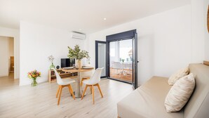A modern living room with a sofa, a dining table with chairs, a TV, and a potted plant. - Apartment 'White Suites' with Shared Pool, Wi-Fi and Air Conditioning (Cala D'or)