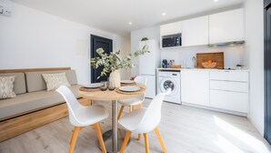 A modern apartment with a dining area, kitchenette, and a sofa. - Apartment 'White Suites 2' with Shared Pool, Wi-Fi and Air Conditioning (Cala D'or)