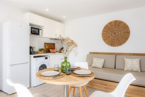 Een moderne keuken met een magnetron, wasmachine en een eethoek met een ronde tafel en stoelen.