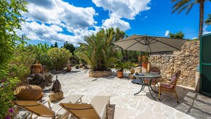 An outdoor patio with stone flooring, a table with chairs, a large umbrella, and potted plants. - Studio Sur – Adults Only in Mallorca with Shared Pool (Manacor)