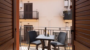 An open balcony with a table and chairs, a window with shutters, and a view of the building's exterior. - Holiday Apartment 'Appartamento A Pigna' with Balcony, Wi-Fi and Air Conditioning (Balestrate)