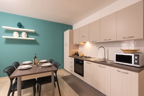 Una cocina moderna con una mesa de comedor, sillas, un microondas y un fregadero.