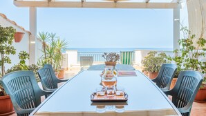 Een terras buiten met een tafel gedekt voor vier personen, omringd door potplanten en stoelen.
