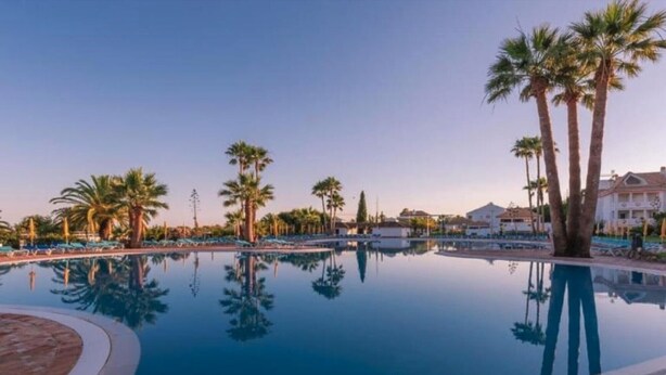 A swimming pool with palm trees and lounge chairs. - Apartment 'Golden Ocean' with Shared Pool, Wi-Fi and Air Conditioning (Cabanas de Tavira)