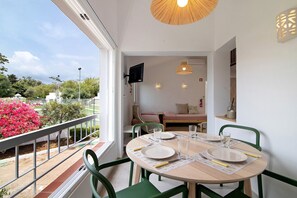 Uma área de refeições com uma mesa posta para dois, cadeiras e vista para o jardim.