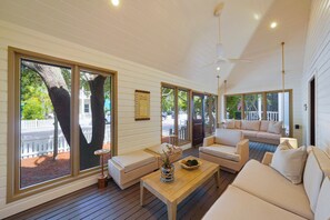 A spacious porch with large windows, wicker furniture, and a ceiling fan.