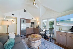 A modern kitchen with stainless steel appliances, a dining area with a round wooden table, and a large window overlooking a beach. - Newly Renovated Beach Cottage in Seaside | King Bed | 194 Ft to the Beach (Santa Rosa Beach)