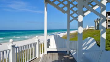Une terrasse en bois avec une balustrade blanche donnant sur une plage.