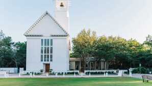 Een witte kerk met een klokkentoren en een gazon ervoor.