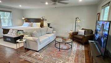 Un dormitorio con cama, sofá blanco, mesa de centro, televisor y alfombra.