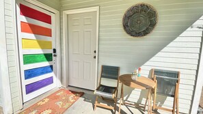 Una puerta principal con un diseño colorido a rayas, una pequeña mesa de madera con sillas y un adorno colgante en la pared.