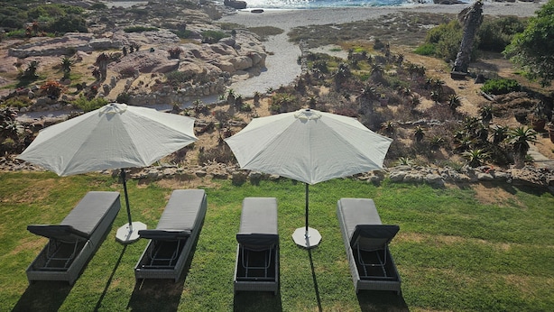 A coastal view with lounge chairs and umbrellas overlooking rocky terrain and the ocean. - Lambert's Bay Beachfront (Lambert's Bay)