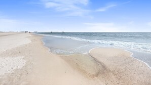 A beach with a pier extending into the water, sandy shore, and clear skies. - Luxury 6-Bedroom Retreat | Pool & Beach Access (Gulf Shores)