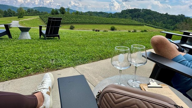 A terrace with a view of a vineyard, outdoor seating, and a table with wine glasses. - Spacious mountain getaway on golf course, near trails, waterfalls & breweries! (Laurel Park)