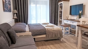 Ein Schlafzimmer mit einem Bett, einem Schreibtisch, einem Sessel, einer Couch und einem Fernseher.