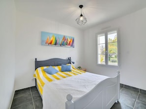 Quarto com cama, janela, quadro e luminária pendente.
