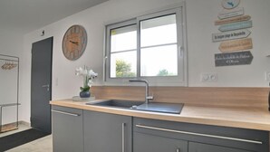 Una cucina moderna con mobili grigi, un piano di lavoro in legno, un lavello e una finestra.