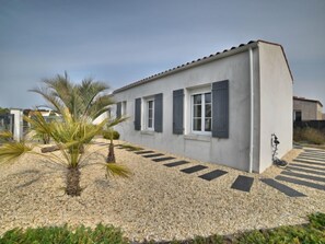 Um edifício moderno com telhado plano, paredes externas brancas e persianas escuras nas janelas.