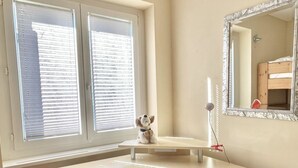 Habitación de esquina con escritorio integrado, un espejo y ventana con persianas.