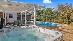 Ein Garten mit Whirlpool, Pool und überdachter Terrasse.