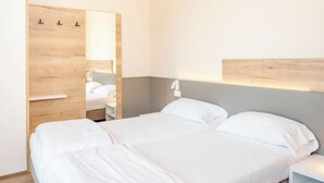 Una habitación de hotel con una cama grande, un armario de madera y una mesita de noche con una lámpara.
