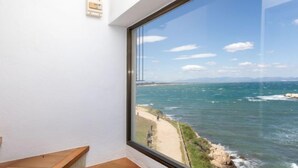Una escalera lleva a una habitación con un amplio ventanal que da a la costa.