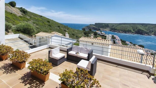 A rooftop terrace with outdoor seating and potted plants, overlooking a coastal landscape with buildings and cliffs. - Garbinell III by Interhome (L'Escala)