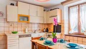 A modern kitchen with white cabinets, a microwave, and a dining area with a table set for four. - Apartment Mila by Interhome (Colico)