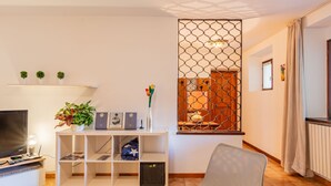 A modern living room with a TV, white shelving unit, and a decorative partition. - Apartment Mila by Interhome (Colico)