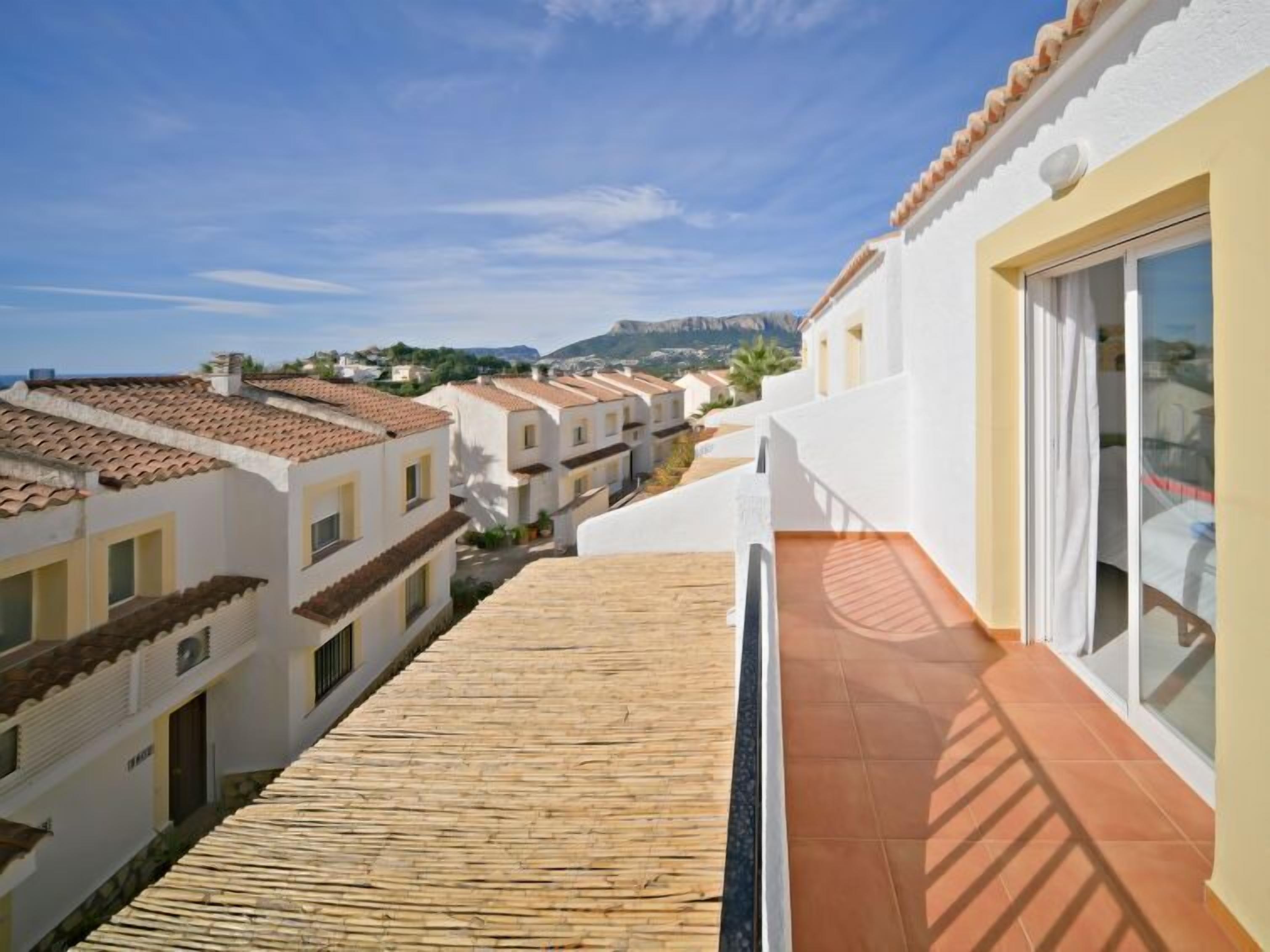 A residential building with a tiled roof and a balcony with a wooden floor.