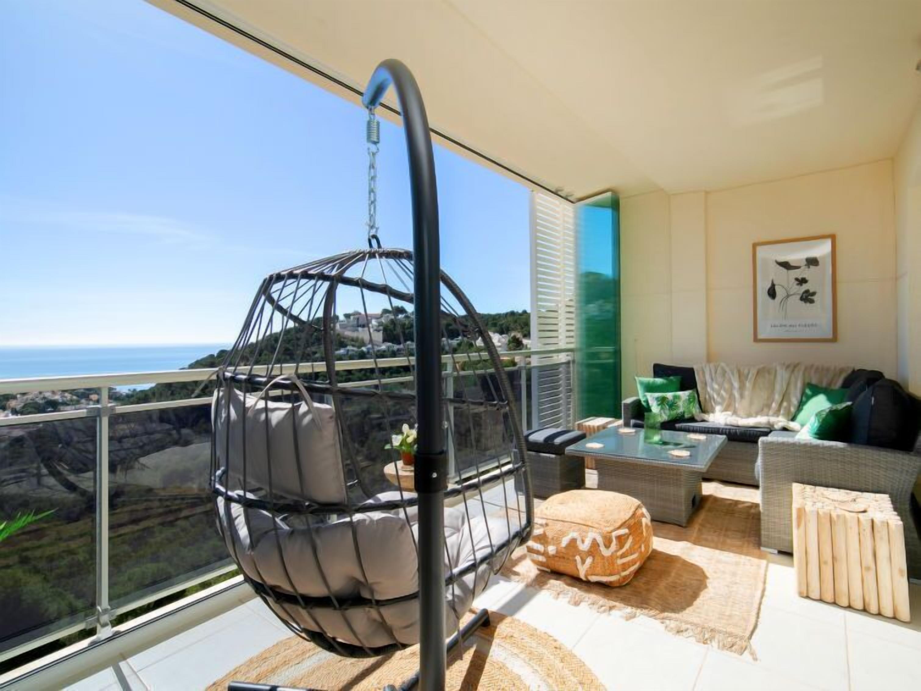 Un balcon avec un fauteuil suspendu, un canapé et une table basse.