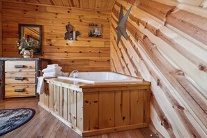 Relax in a spacious bathroom with a large bathtub, wooden vanity, and a decorative star on the wall.
