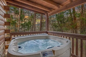 Relax in a serene hot tub on a deck surrounded by a forest.