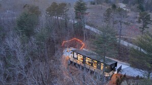 Eine Hütte mit einer Veranda, umgeben von Bäumen und einem Berg im Hintergrund.