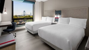 Habitación de hotel moderna con dos camas, un escritorio y una silla.