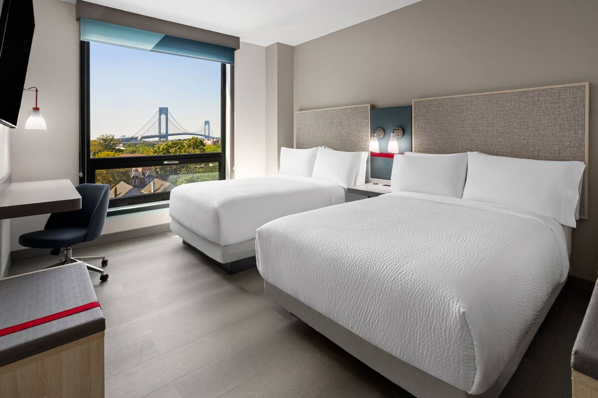 Une chambre d’hôtel moderne avec deux lits, un bureau et une chaise.