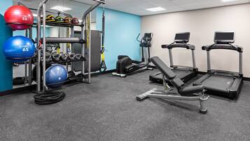 A gym with treadmills, a weight bench, and various exercise balls.