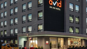 Un edificio moderno con un cartel grande que dice "Avid IHG Hotel" y una entrada bien iluminada.