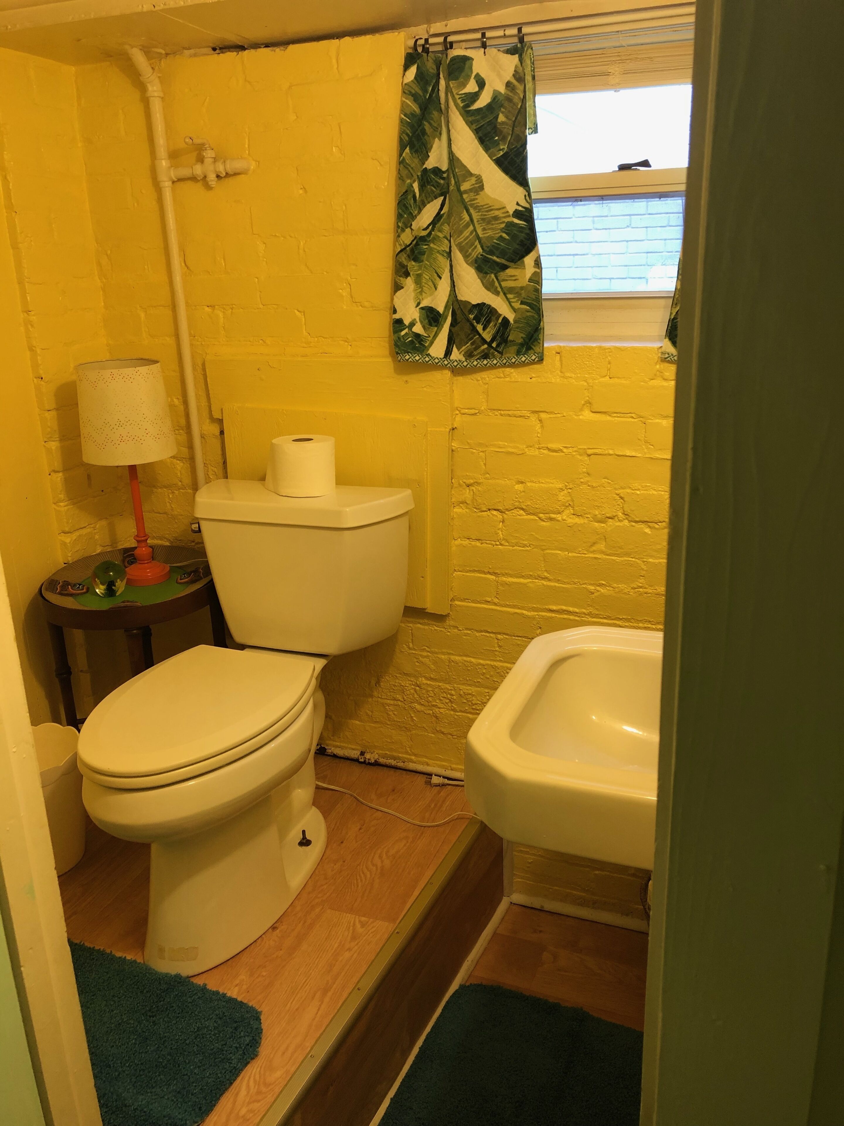 A small bathroom with a toilet, bidet, and a window with a view.