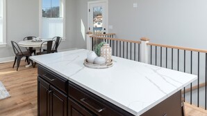 A modern kitchen with a large island, dark cabinetry, and a dining area with a round table and chairs. - IN THE HEART OF DEWEY BEACH - 2002 Bayard Ave (Dewey Beach)