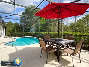 A covered outdoor pool area with a table and chairs, surrounded by a glass enclosure. - Modest Charmer W/ Private Pool (Clermont)