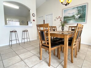 A dining area with a wooden table and chairs, a potted plant, and a painting on the wall. - Modest Charmer W/ Private Pool (Clermont)