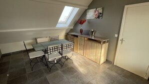 A dining area with a glass table and chairs, a wooden cabinet, and a skylight. - A 10km de Bxl ,2ch, Pour 7 ,parck,meublé,bus,train (Asse)