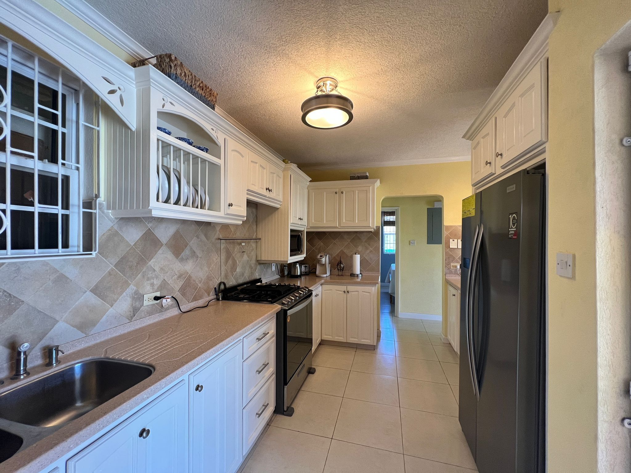 A kitchen with white cabinets, a black refrigerator, and a tiled backsplash.
