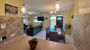 A modern kitchen with a dining area, a living room, and a large window.
