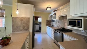 A kitchen with white cabinets, a stainless steel stove, a microwave, and a refrigerator.