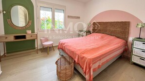 A bedroom with a bed, a vanity with a mirror, a chair, and a window with blinds.