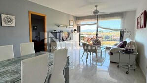 A spacious living area with a dining table, chairs, a sofa, and a balcony with a view. - Apartament in Edif. Alba de Cambrils (Cambrils)